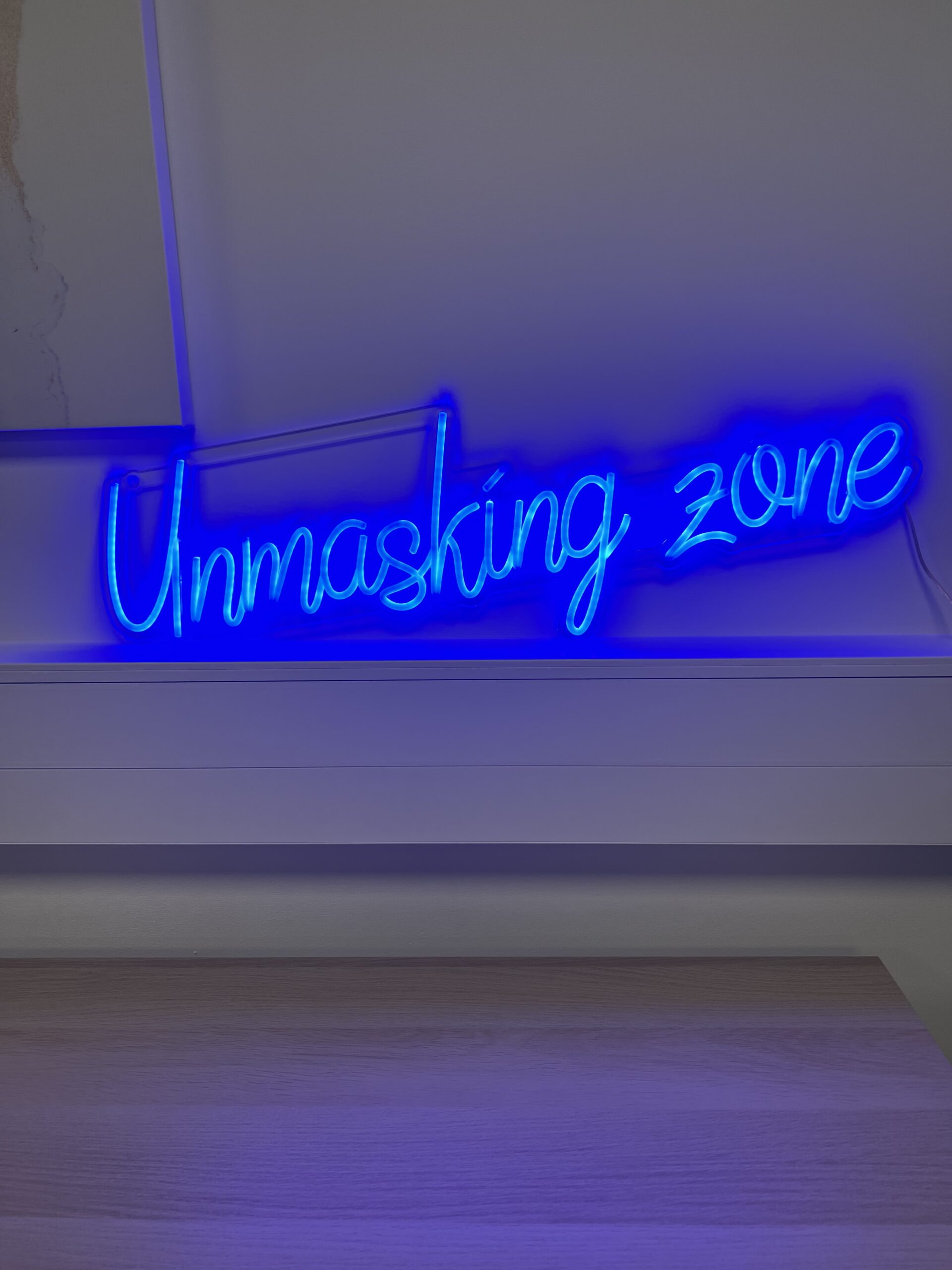 Neon sign saying Unmasking Zone